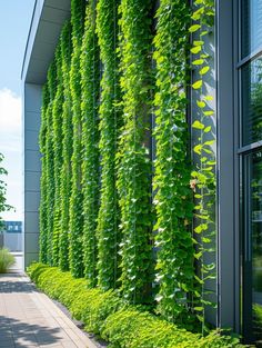 a building covered in green plants next to a sidewalk