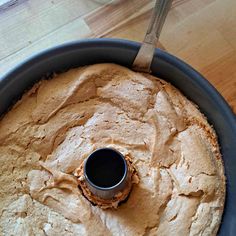 a round pan filled with food on top of a wooden table next to a knife