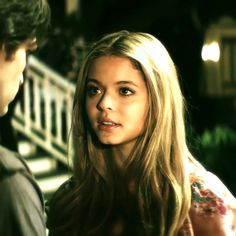 a woman standing next to a man in front of stairs