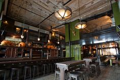 the interior of a restaurant with wooden tables and stools in front of green walls