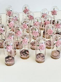 there are many pink roses in glass vases with flowers inside them on the table