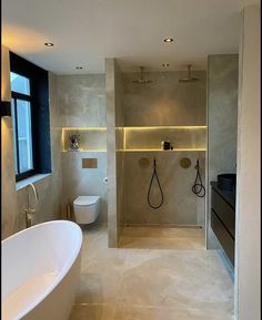 a bathroom with a tub, toilet and shower in it's center wall is lit by recessed lighting