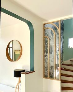 a living room filled with furniture next to a stair case and mirror on the wall