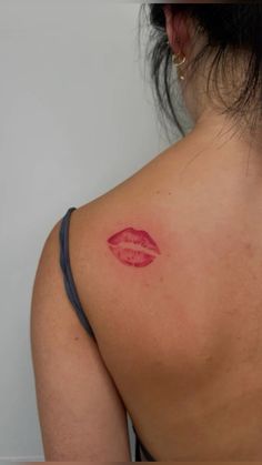 a woman's back with a red lip tattoo on it