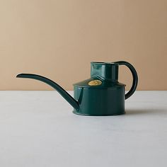 a green watering can sitting on top of a table