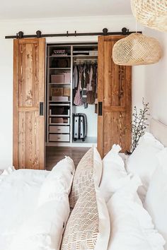 a bed with white sheets and pillows in front of two wooden closets that are open