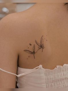 the back of a woman's shoulder with two dragonflies on it