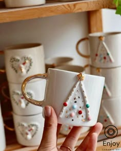 a hand holding a coffee mug with a christmas tree on it