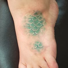 the foot is covered in green water and has fish tattoos on it's toes