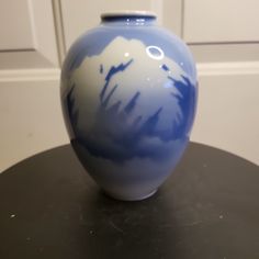 a blue and white vase sitting on top of a black table next to a door