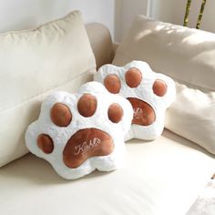 three pillows with paw prints on them are sitting on a couch next to a pillow