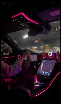 the interior of a car with pink lights on it and a man driving in front of him