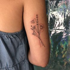 a woman with a tattoo on her arm holding a flower in front of her shoulder