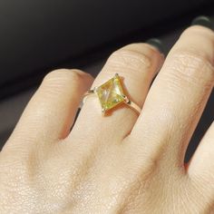 a woman's hand with a yellow diamond ring on it