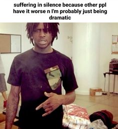 a man with dreadlocks standing in a living room next to a pile of clothes