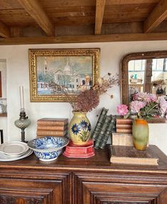 a table with books and vases on top of it in front of a mirror