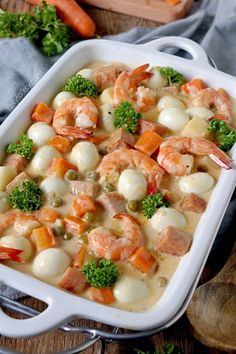 a white casserole dish filled with shrimp and veggies