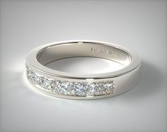 a white gold wedding ring with princess cut diamonds on the side and channeled sides