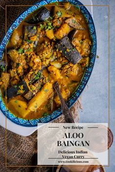 a blue bowl filled with aloo baingan on top of a table