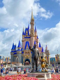 a statue of walt and mickey mouse in front of the sleeping beauty castle at disney world