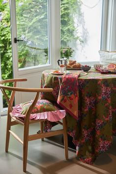 the table is set for two with plates and fruit on it, along with an open window