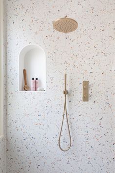 a bathroom with white walls and colorful speckles on the wall, including a shower head