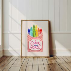 an art print with crayons on it in front of a white wall and wooden floor