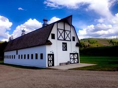 a large white barn with black trim and windows