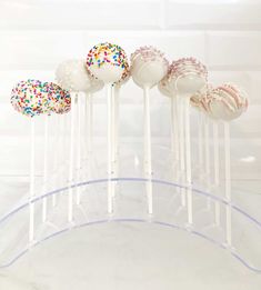 cake pops with sprinkles on them in a clear plastic holder against a white background