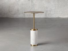 a white marble and brass side table on a grey floor