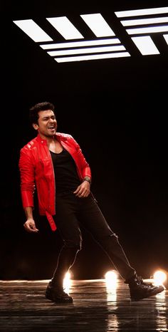 a man in red jacket and black pants on stage