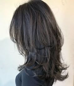 the back of a woman's head with long, dark hair and wavy bangs