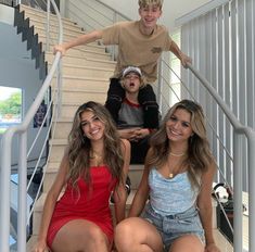 three young people are sitting on the stairs and one man is standing behind them with his arms in the air