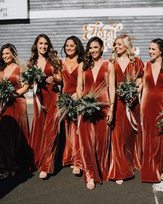 a group of women standing next to each other in front of a building holding bouquets