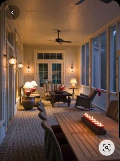 a long table with candles on it sitting in front of some chairs and windows next to a door