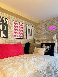 a bed with white sheets and red pillows in a room that has brick walls on both sides