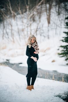 a woman is standing in the snow with her arms wrapped around her body and looking into the distance