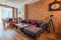 a living room filled with furniture next to a brick wall and wooden floored floors