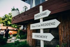 a wooden sign that says welcome to the wedding ceremony with two people in the background