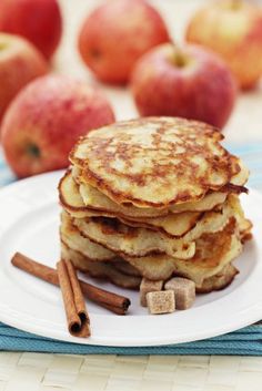 a stack of pancakes sitting on top of a white plate next to cinnamon sticks and apples