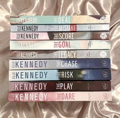 a stack of books sitting on top of a bed next to a pink sheet covered wall