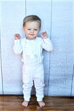 a little boy standing in front of a wooden wall