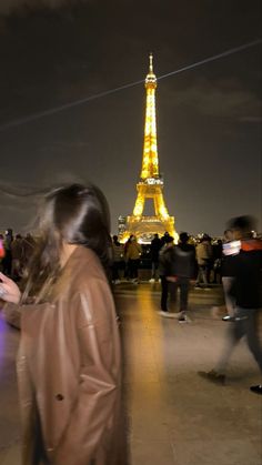 people standing in front of the eiffel tower at night