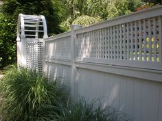 a white picket fence next to some tall grass