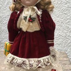 a doll with blonde hair wearing a red dress and white laces on it's head