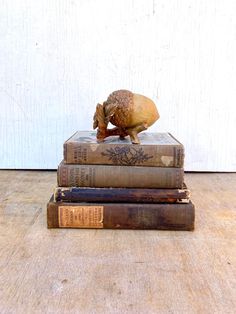 three books stacked on top of each other with an animal figurine atop them