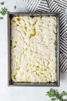 a square pan filled with white cheese and herbs