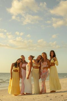 four beautiful women standing on the beach in front of the ocean at sunset or sunrise