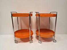 two orange chairs sitting next to each other on wheels