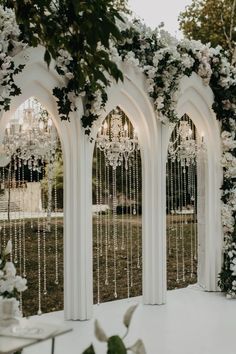 an outdoor ceremony with white flowers and chandeliers